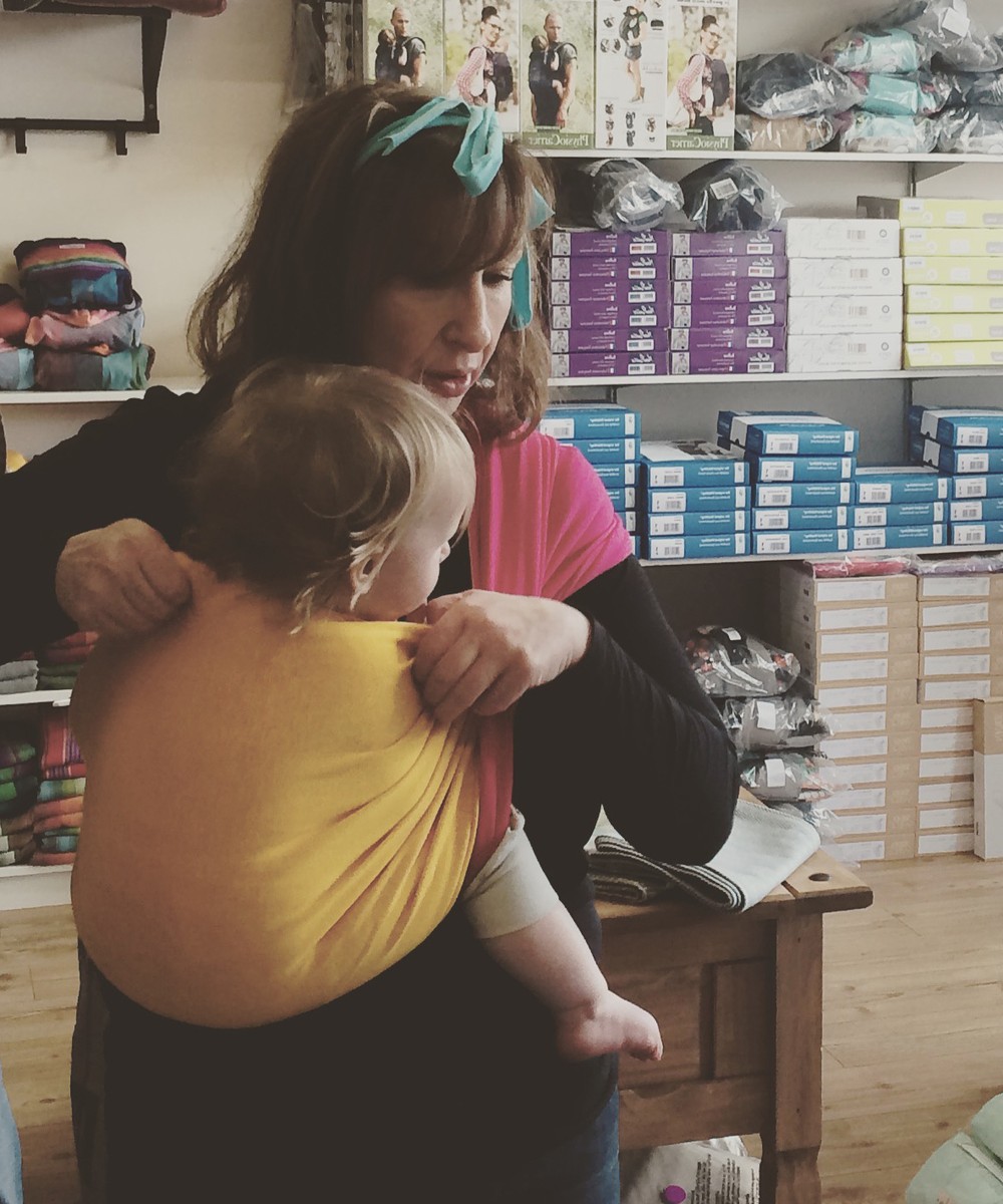 Babywearing NI consultant fitting a baby into a sling outdoors